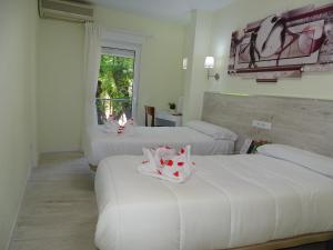 グアダラハラにあるPensión El Otero 2のベッド3台と窓が備わるホテルルームです。