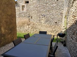 CéresteにあるLa maison Bleueの石壁前のテーブルと椅子