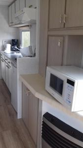 a kitchen with white cabinets and a white microwave at Middenin in Grijpskerke