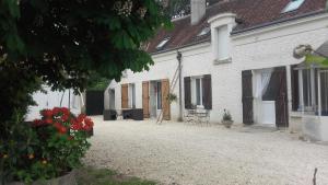une cour d'une maison blanche avec des chaises et des fleurs dans l'établissement Les Hardilles, à Châtillon-sur-Cher