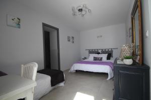 - une chambre dotée d'un lit avec des draps violets et un miroir dans l'établissement Les Hardilles, à Châtillon-sur-Cher