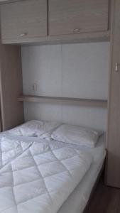 Una cama con sábanas blancas y almohadas. en Middenin, en Grijpskerke