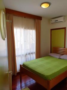 a bedroom with a green bed and a window at Amalia Apartments in Paramaribo +31 photos