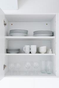 a white cabinet with plates and glasses and dishes at athome apartments in Aarhus