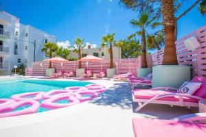 een zwembad met roze ligstoelen en een zwembad bij Apartamentos Wi-Ki-Woo in San Antonio