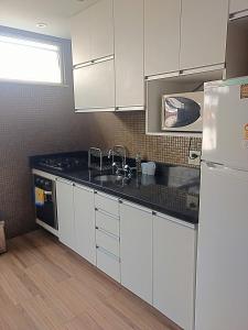 uma cozinha com armários brancos, um lavatório e um frigorífico em Alberto de Campos 66 no Rio de Janeiro