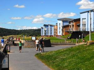 a group of people walking down a sidewalk near buildings at Beach Front Ground Floor Apartment in Llanelli