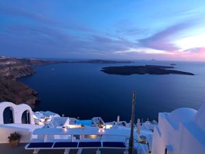 una vista del océano por la noche con edificios blancos en Katikies Chromata Santorini - The Leading Hotels of the World, en Imerovigli