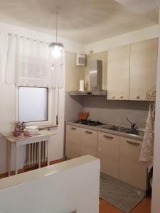 een keuken met witte kasten, een wastafel en een raam bij Appartamenti Mori in Belluno