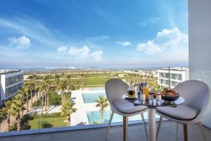 einen Balkon mit einem Tisch und Stühlen sowie Poolblick in der Unterkunft The View Bouznika in Bouznika