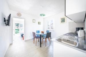 a kitchen with a sink and a table with chairs at Apartmani Ada 1 in Povlja