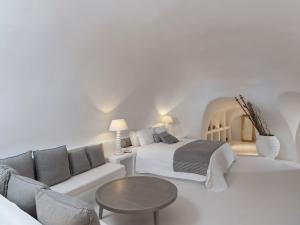 a white bedroom with a bed and a couch at Katikies Chromata Santorini - The Leading Hotels of the World in Imerovigli