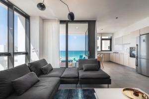 a living room with a couch and a kitchen with the ocean at Hayarkon 29 - Next Royal Beach in Tel Aviv