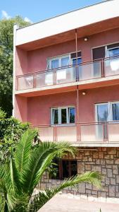 ein rotes Gebäude mit einem Balkon und einer Palme in der Unterkunft Nora Wine House in Split