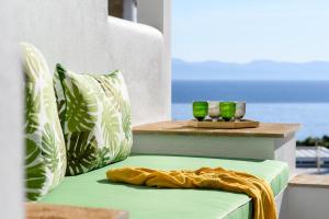 einem grünen Stuhl mit zwei grünen und weißen Kissen in der Unterkunft Villa D'Oro - Luxury Villas & Suites in Paliouri