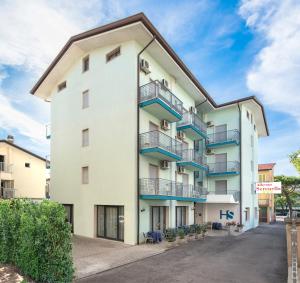 a white apartment building with blue balconies at Hotel Serenella in Lido di Jesolo