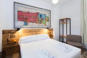 a bedroom with a white bed and a painting on the wall at Gran H La Marina in Altea
