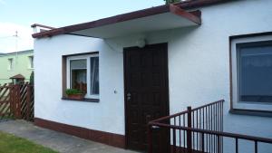 ムロンゴヴォにあるDomek w ogrodzieの茶色の扉と窓のある白い家