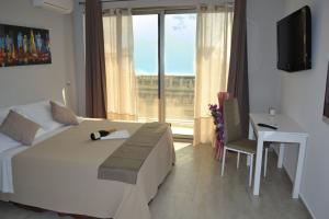 a bedroom with a bed and a desk and a window at B&B Varadero in Milazzo