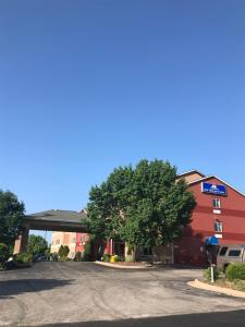 un estacionamiento frente a un edificio con un árbol en Americas Best Value Inn and Suites Saint Charles, en St. Charles