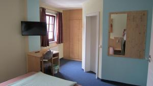 a room with a bed and a desk and a mirror at Hotel Zum Schwarzen Bär in Hermsdorf