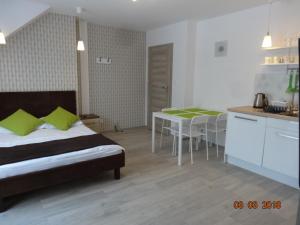 a bedroom with a bed and a kitchen with a table at Villa Cork in Dębki