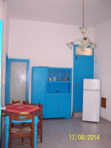 a kitchen with blue cabinets and a table and a refrigerator at Ni La Za Ciccina in Castellammare del Golfo