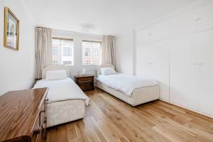 sypialnia z 2 łóżkami i drewnianą podłogą w obiekcie Prime London Apartment, Oxford Circus w Londynie