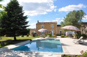 a swimming pool in front of a house with umbrellas at Chambre d'hôtes Sauternais in Pujols-sur-Ciron