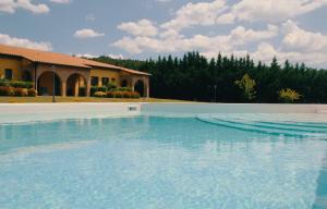 une grande piscine d'eau en face d'une maison dans l'établissement Le Terre Di Toscana, à Casa Pallini