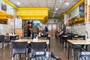 a restaurant with tables and chairs and people in the kitchen at Hotel Monreal Jumilla in Jumilla