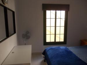 Schlafzimmer mit einem Bett, einem Tisch und einem Fenster in der Unterkunft Caleta Paraiso - Lovely Coastal Apartment in Costa de Antigua