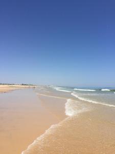 een strand met mensen die op het zand en de oceaan lopen bij T1 Praia de Altura in Altura