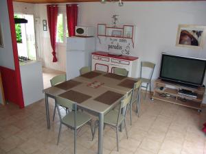 eine Küche mit einem Tisch und Stühlen sowie einem TV in der Unterkunft Les Petits Prés in Vitrac