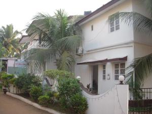 a white house with a palm tree in front of it at Sugar Plum Macedo Palms in Baga