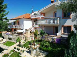 a house with a balcony and a yard with plants at Apartments Katičin in Poljana