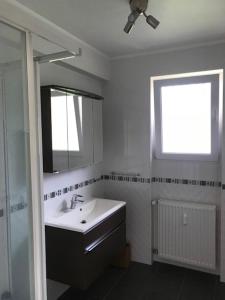 een badkamer met een wastafel, een spiegel en een raam bij Waarkstrooss 12 in Welscheid