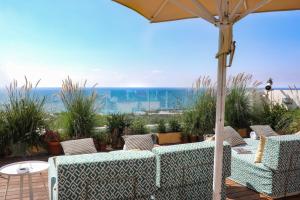 a patio with two couches and an umbrella and the ocean at Melody Hotel - an Atlas Boutique Hotel in Tel Aviv