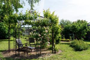 un jardín con un arco con una silla y rosas en Villa Chanelle, en Les Rosiers