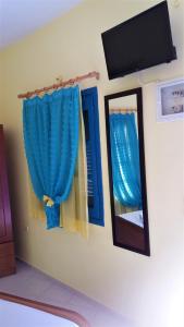 a room with blue curtains and a mirror and a tv at Mouragio Studios in Tyros