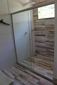a shower with a glass door in a bathroom at PachaMama Flats - Taipu de Fora in Barra Grande