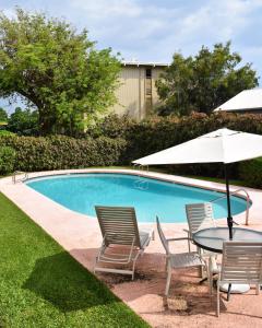uma mesa com cadeiras e um guarda-sol ao lado de uma piscina em Holualoa Garden 103 em Kailua-Kona
