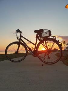 una bicicleta estacionada frente a la puesta de sol en Apartments Laura 1, en Privlaka