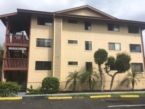 a apartment building with a balcony and trees at Holualoa Garden 103 in Kailua-Kona
