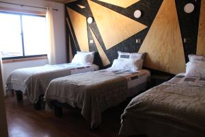 a room with three beds and a large window at Residencial del Maule in Linares