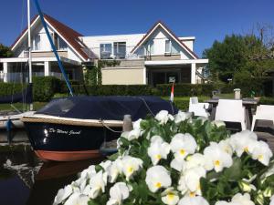 een boot aangemeerd voor een huis met witte bloemen bij Villa Envie in Terherne