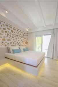 a white bedroom with a large bed in a room at La Pierre in Limenaria