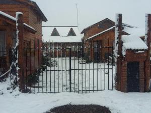 un cancello di ferro nella neve accanto a un edificio di Cabañas Natanael a Trevelin