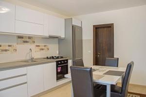 a kitchen with white cabinets and a table with chairs at I Love Bran House in Şimon
