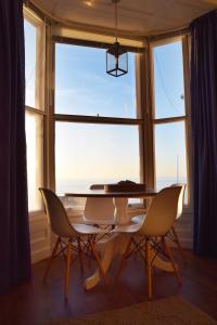 jadalnia ze stołem i krzesłami oraz dużym oknem w obiekcie Awel Mor 3 Luxury Apartment w Aberystwyth